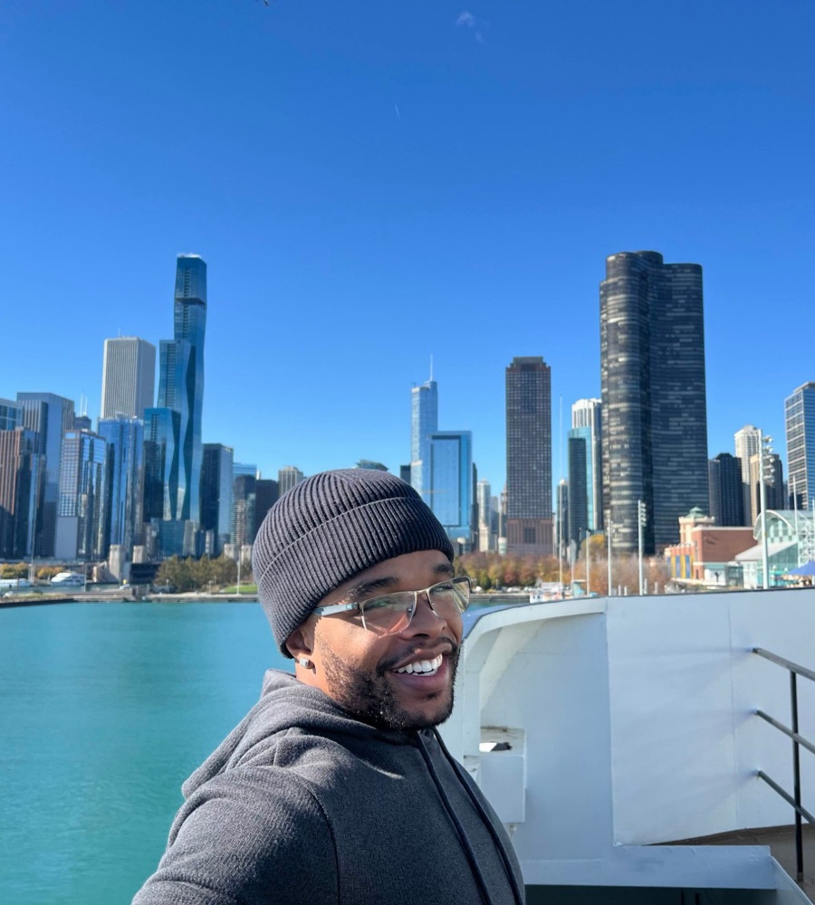 Caleb Butler smiling on a boat with the Chicago skyline behind him
